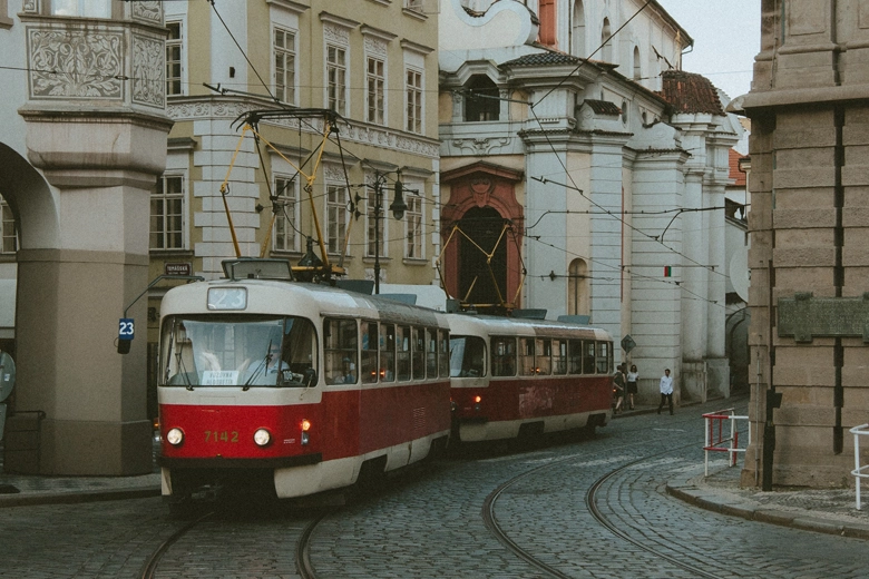 Dynamic red tram in motion, gliding gracefully in front of charming buildings against the backdrop of Prague's cityscape.